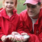 A father and daughter holding a fish