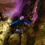 A man caving and wearing caving gear.